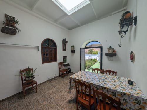 Comedor luminoso en la villa El Recuerdo de Finca Villanueva con sillas de madera, mantel floral, claraboyas y vistas al océano