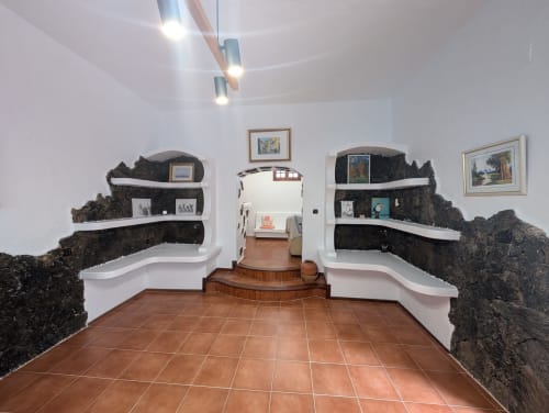 Sala de la villa El Recuerdo en Finca Villanueva con rocas volcánicas, estantes blancos y piso de terracota
