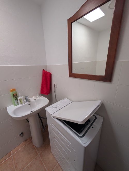 Baño de la villa El Recuerdo en Finca Villanueva Lanzarote con lavabo, espejo y lavadora-secadora