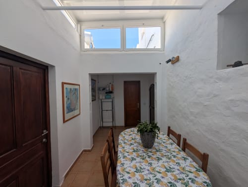 Comedor luminoso en Finca Villanueva con tragaluces, mesa de madera, planta en maceta y pisos de terracota en Mala, Lanzarote