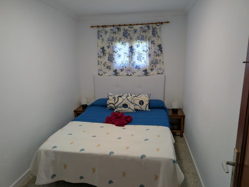 Acogedora habitación en la villa Finca Villanueva Lanzarote con ropa de cama azul, cortinas florales y muebles de madera en Mala
