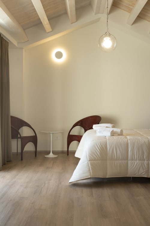 Modern suite bedroom at Hotel Belvedere Resort with bed, wooden chairs, pendant lighting, and minimalist design in