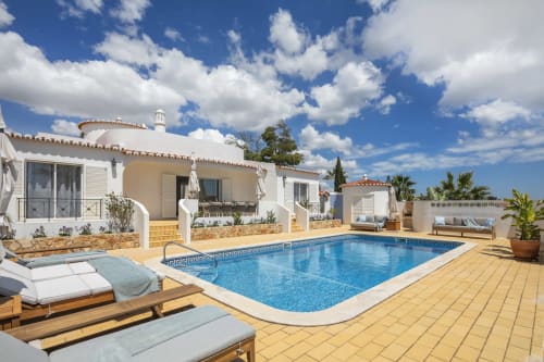 MarVillas Rentals Lagoa villa with blue swimming pool, white loungers, and Mediterranean-style architecture under blue sky