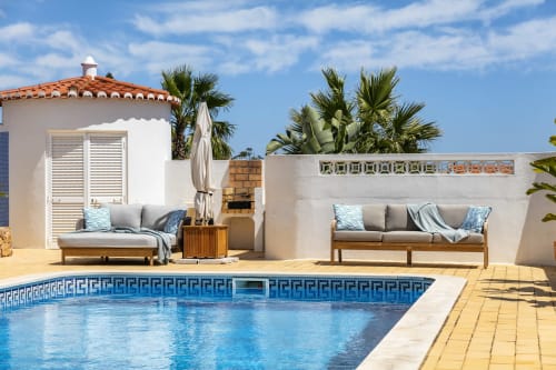 Luxury poolside terrace at MarVillas Rentals in Lagoa with lounge furniture, palm trees, and blue Mediterranean-style pool