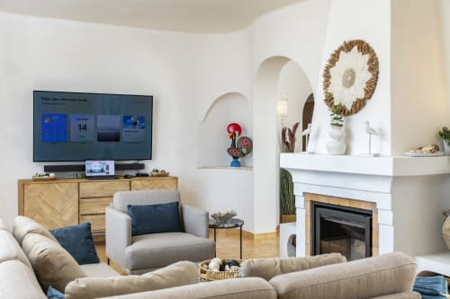 Modern living room at MarVillas Rentals in Lagoa with cream sofa, fireplace, wooden TV console, and decorative arch alcove
