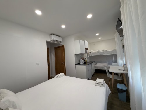Modern hostel room at Vila Alexandra in Costa da Caparica with bed, kitchenette, workspace, and bunk bed