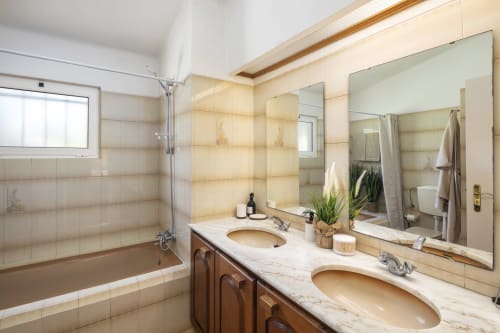 Elegant bathroom at MarVillas Rentals in Lagoa with dual vanities, marble countertop, and modern glass shower enclosure