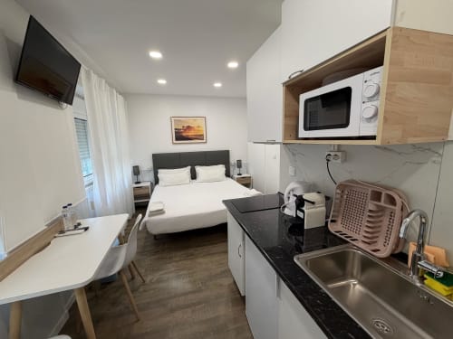 Compact studio room at Vila Alexandra hostel in Costa da Caparica with bed, kitchenette, TV, and workspace