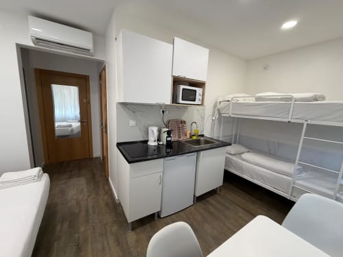 Modern hostel room at Vila Alexandra with bunk beds, kitchenette, and air conditioning in Costa da Caparica