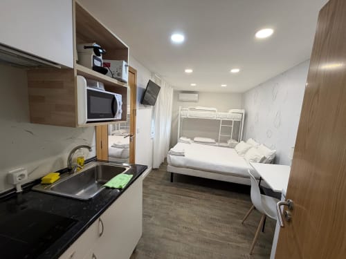 Vila Alexandra hostel room in Costa da Caparica with kitchenette, bunk bed, TV, and modern amenities
