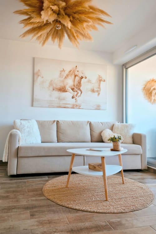 Salon moderne de l'appartement Sable & Pampas à Carnon-Plage avec canapé beige, table basse blanche et décoration équestre