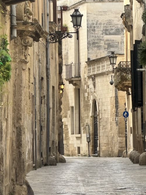 Charming narrow stone alley in Lecce's historic center with traditional street lamps and architecture