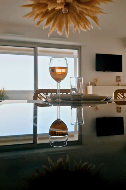 Table à manger contemporaine à l'appartement Sable & Pampas à Carnon-Plage avec verre de vin et vue côtière par les fenêtres