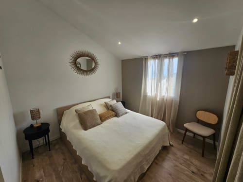 Chambre moderne de la villa Altezza à Brando avec vue mer, lit queen-size, miroir soleil et lumière naturelle des grandes fenêtres
