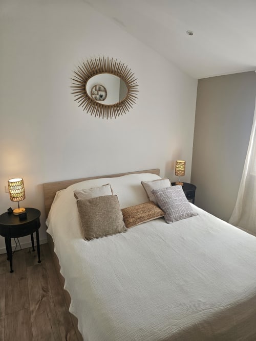 Chambre moderne à la villa Altezza à Brando avec lit blanc, miroir soleil décoratif et décoration neutre