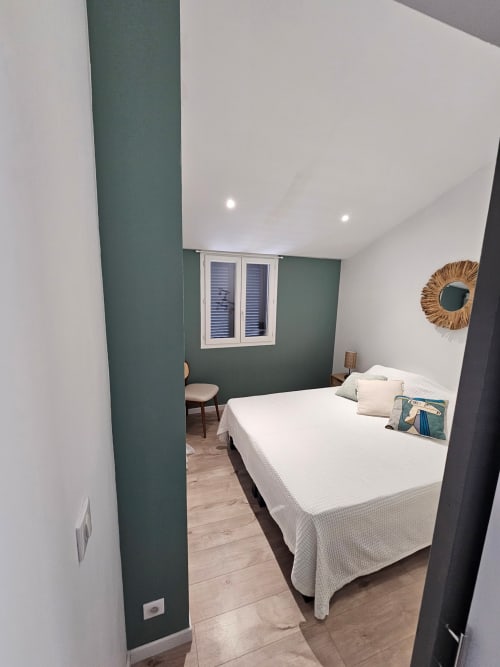 Chambre moderne à la villa Altezza à Brando avec mur d'accent vert, lit blanc, parquet et vue sur mer