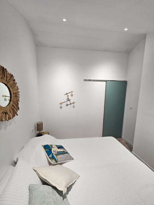 Chambre moderne de la villa Altezza à Brando avec lit blanc, miroir décoratif et porte coulissante verte
