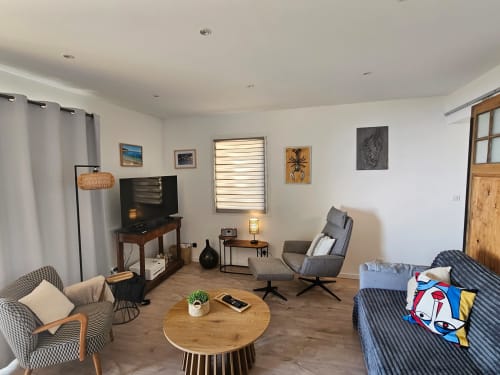 Salon moderne de villa à Brando avec vue sur mer, aménagé confortablement avec canapé, TV, table ronde en bois et design contemporain