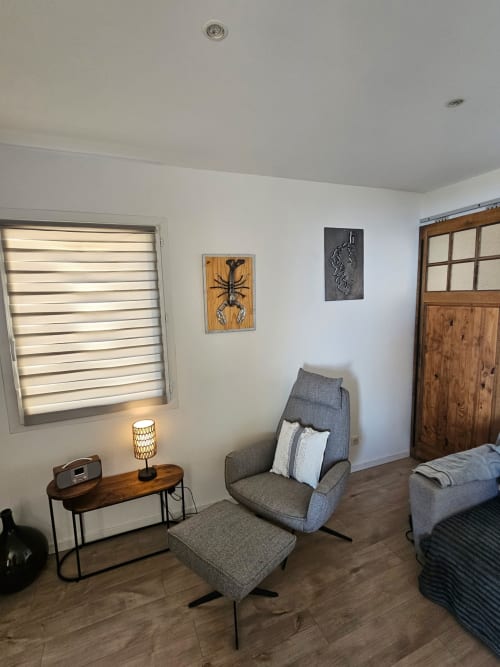 Chambre moderne à la villa Altezza à Brando avec fauteuil gris, mobilier en bois et vue sur mer