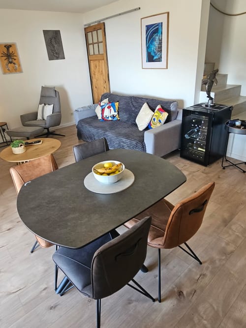 Salle à manger contemporaine de la villa Altezza avec vue mer, table ovale noire, chaises en cuir et canapé gris aux touches colorées