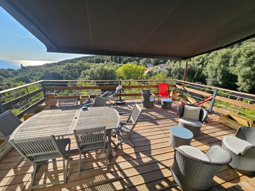 Spacieuse terrasse de la villa Altezza à Brando avec mobilier de salle à manger, transats et vue panoramique sur la côte corse