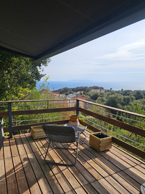 Balcon de la villa Altezza à Brando avec vue mer, terrasse en bois, chaise longue et paysage côtier
