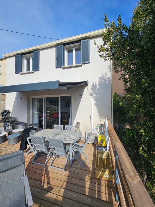 Terrasse de villa moderne à Brando avec table à manger, chaises longues et vue sur mer