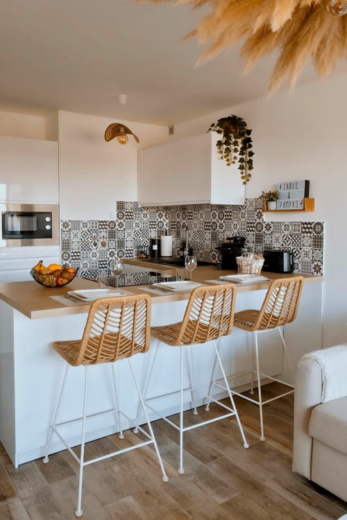 Cuisine moderne de l'appartement Sable & Pampas à Carnon-Plage avec carrelage motifs, tabourets bois et décoration naturelle