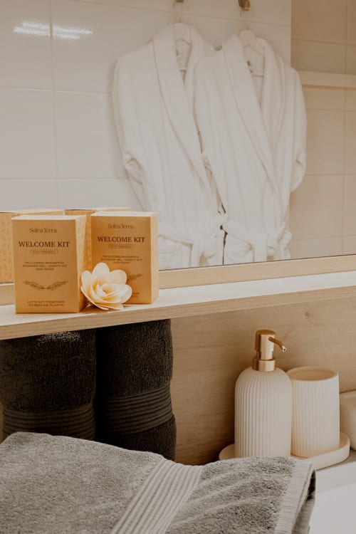 Vanité de salle de bain chez Sable & Pampas avec kits Solca Terra, peignoirs blancs et articles de toilette