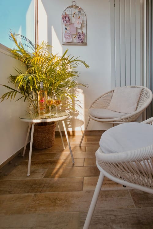 Appartement moderne et lumineux à Sable & Pampas avec chaises tissées blanches, palmier en pot et cage à oiseaux décorative à Carnon-Plage