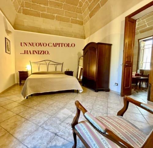 Spacious bedroom at HABITARE Lecce with decorated walls, wooden furniture, and vaulted brick ceiling
