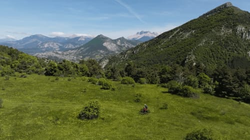 Vélotouriste profitant des prairies alpines verdoyantes et des pics boisés près du Petit Bégou, Saint-Auban-d'Oze