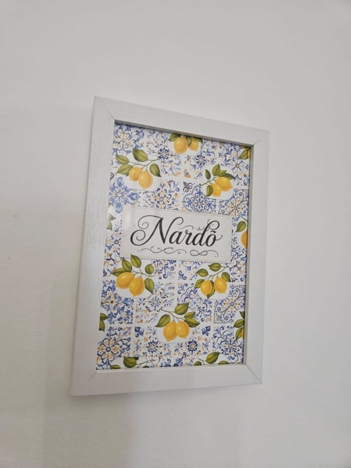 Cuadro decorativo enmarcado con texto 'Nardò', motivos florales azules y limones amarillos en marco blanco