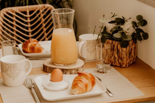 Elegant breakfast table at Sable & Pampas with croissants, juice, coffee, and fresh flowers at Carnon-Plage