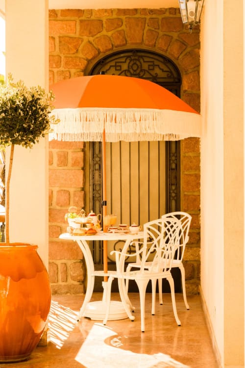Area lounge della terrazza dell'Hôtel Villa Martini ad Ajaccio con ombrellone arancione, sedia bianca e vista mare attraverso arcata