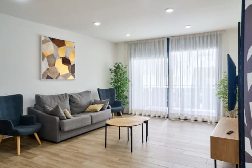 Salón moderno en apartamento Tr3sor 11, Calella con sofá gris, mesa de madera y ventanales luminosos con cortinas