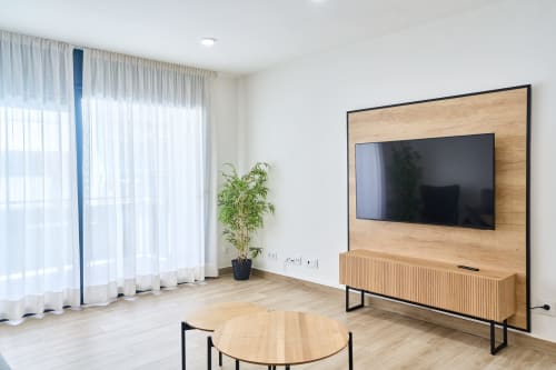 Sala de estar moderna en apartamento Tr3sor Homes, Calella con TV mural, mueble de madera, mesa redonda y