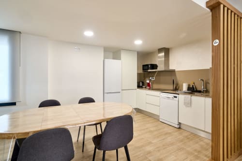 Moderna cocina y comedor del apartamento Tr3sor 11 en Calella, con muebles blancos, mesa de madera y sillas negras