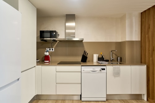 Cocina moderna en apartamento Tr3sor 11, Calella: mobiliario blanco, electrodomésticos acero inoxidable, microondas, lavavajillas