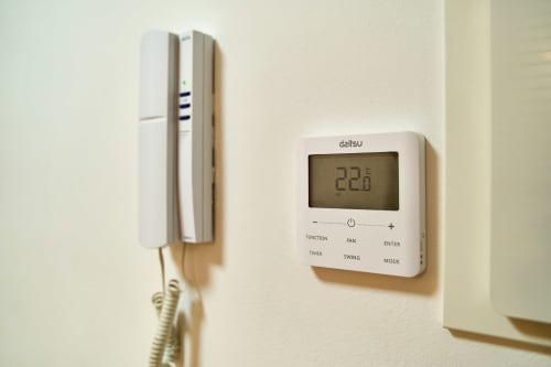 Termostato digital mostrando 22.8°C junto al portero automático en apartamento Tr3sor Homes, Calella