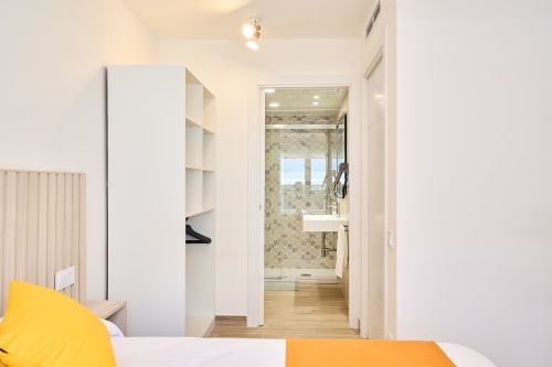 Moderno dormitorio con ropa de cama amarilla, armario blanco y baño privado en el apartamento Tr3sor 11 de Calella