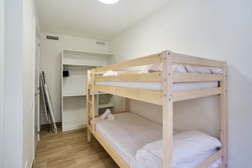 Litera de madera clara con ropa de cama blanca en dormitorio moderno del apartamento Tr3sor Homes, Calella