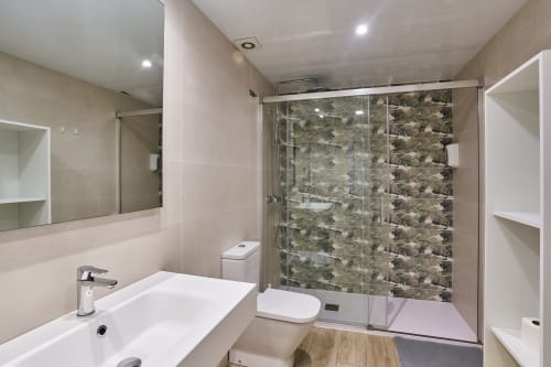 Baño moderno en apartamento Tr3sor B2, Calella con ducha a ras de suelo, lavabo blanco, inodoro y calefacción en el piso