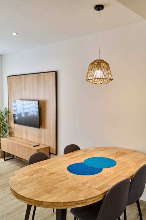 Comedor moderno del apartamento Tr3sor B2 en Calella con mesa de madera, manteletas azules y lámpara colgante tejida