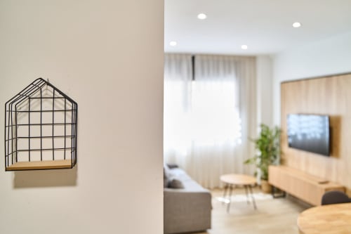 Interior moderno del apartamento en Tr3sor Homes, Calella con estantería de pared en forma de casa y sala luminosa