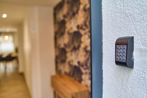 Sistema de acceso digital montado en pared texturizada blanca en el pasillo del apartamento Tr3sor Homes, Calella.