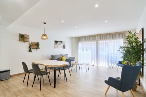 Salón moderno del apartamento Tr3sor 13 en Calella con comedor, asientos, plantas y ventanales luminosos