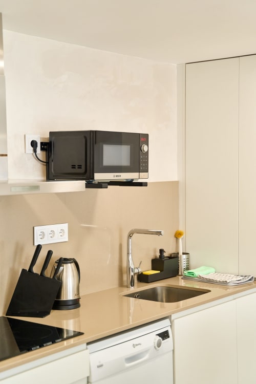 Moderna cocina del apartamento Tr3sor Homes en Calella con microondas, fregadero, bloque de cuchillos y accesorios de encimera