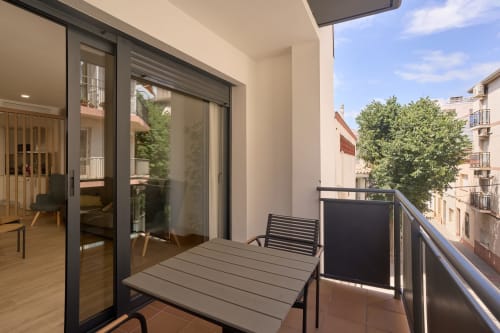 Balcón de apartamento moderno en Calella con mesa de comedor, sillas y vistas a la ciudad en Tr3sor Homes