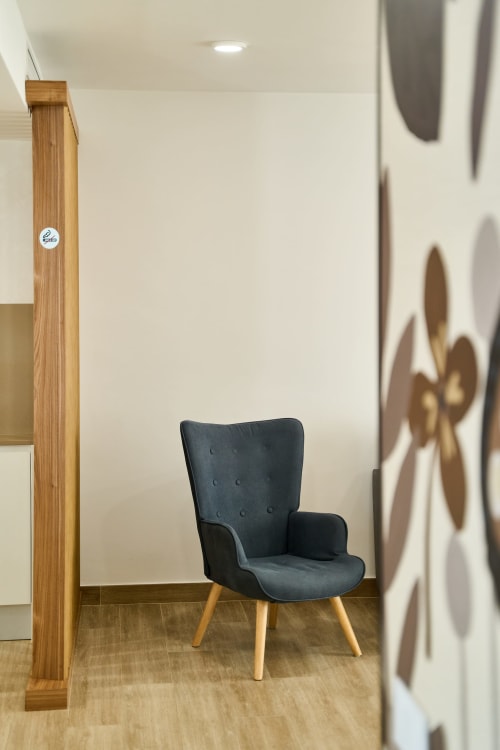 Sala de estar moderna en Tr3sor Homes, Calella, con silla tapizada oscura y detalles de madera